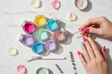 A hand with colorful painted nails holding a fine brush over vibrant jars of the best nail dip powder nails set.