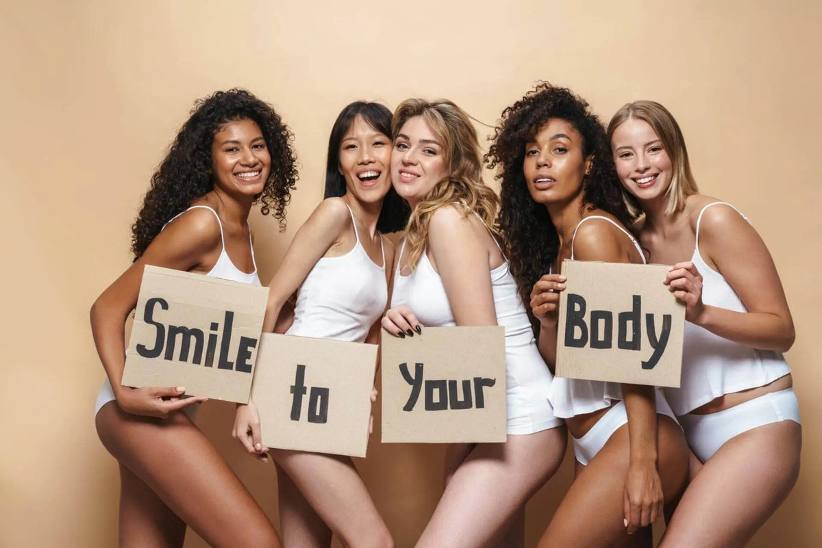 Five women in white underwear hold smile to your body signs promoting royalessencelux body care essentials collection