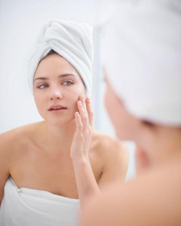 Woman with white towel wrapped around her head in royalessencelux skin care for expert skin hydration and wellness care