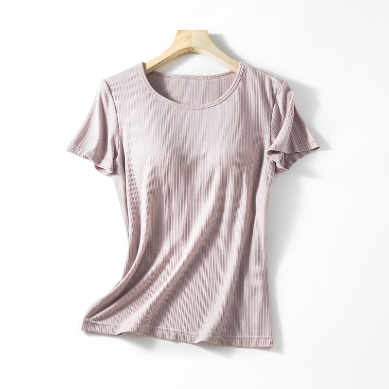A soft mauve ribbed knit short-sleeved women’s summerdale loose-fitting padded chest top with a round neckline hanging on a wooden hanger.