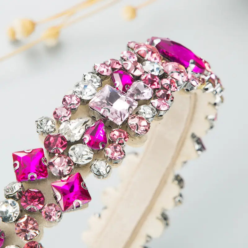 A baroque vintage court style crystal headband featuring sparkling pink and clear rhinestones with a scalloped edge.