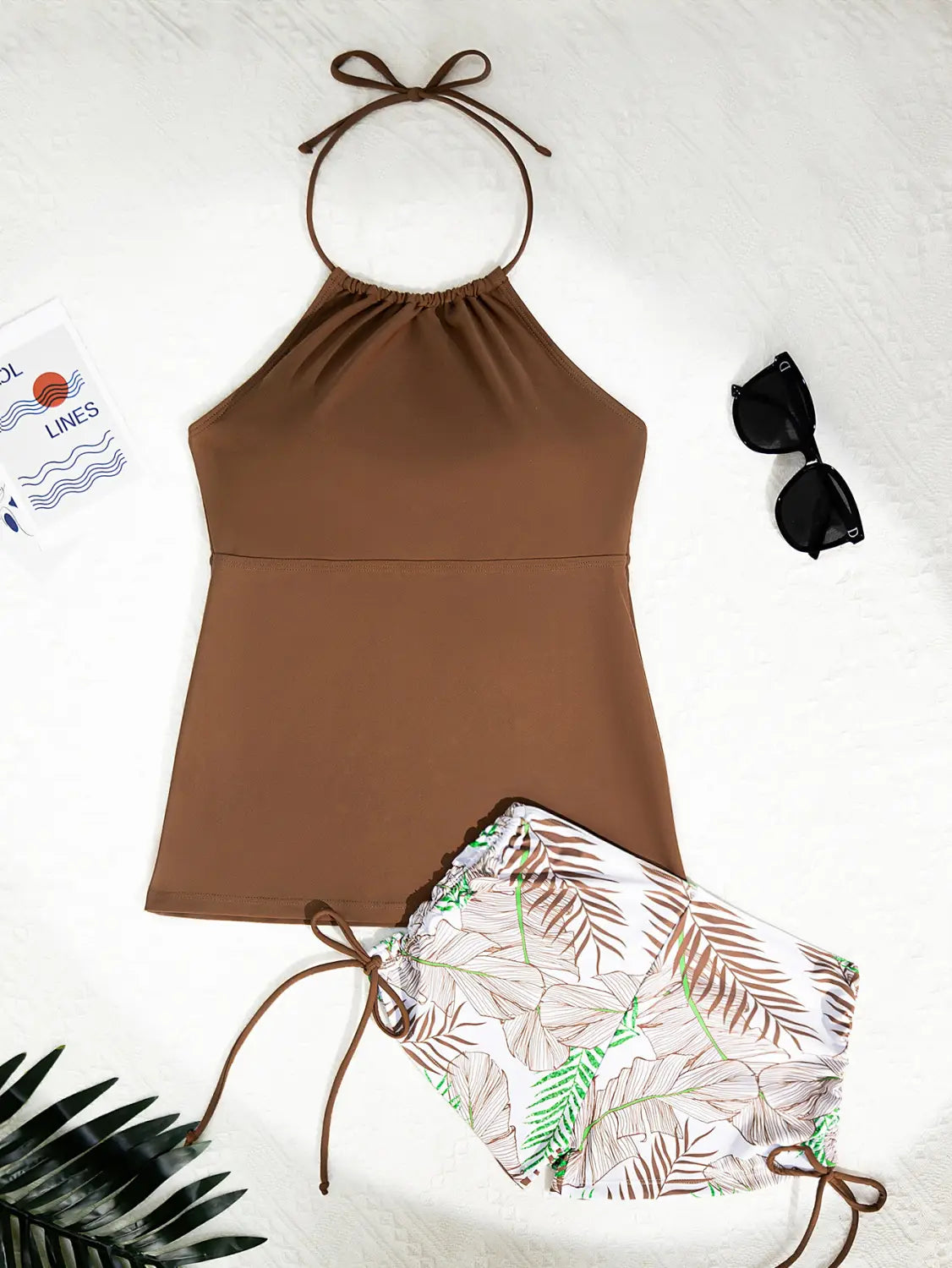 brown halterneck printed halter split swimsuit featuring a tied neckband halter top and matching drawstring shorts with tropical leaf patterns in green beige and white.