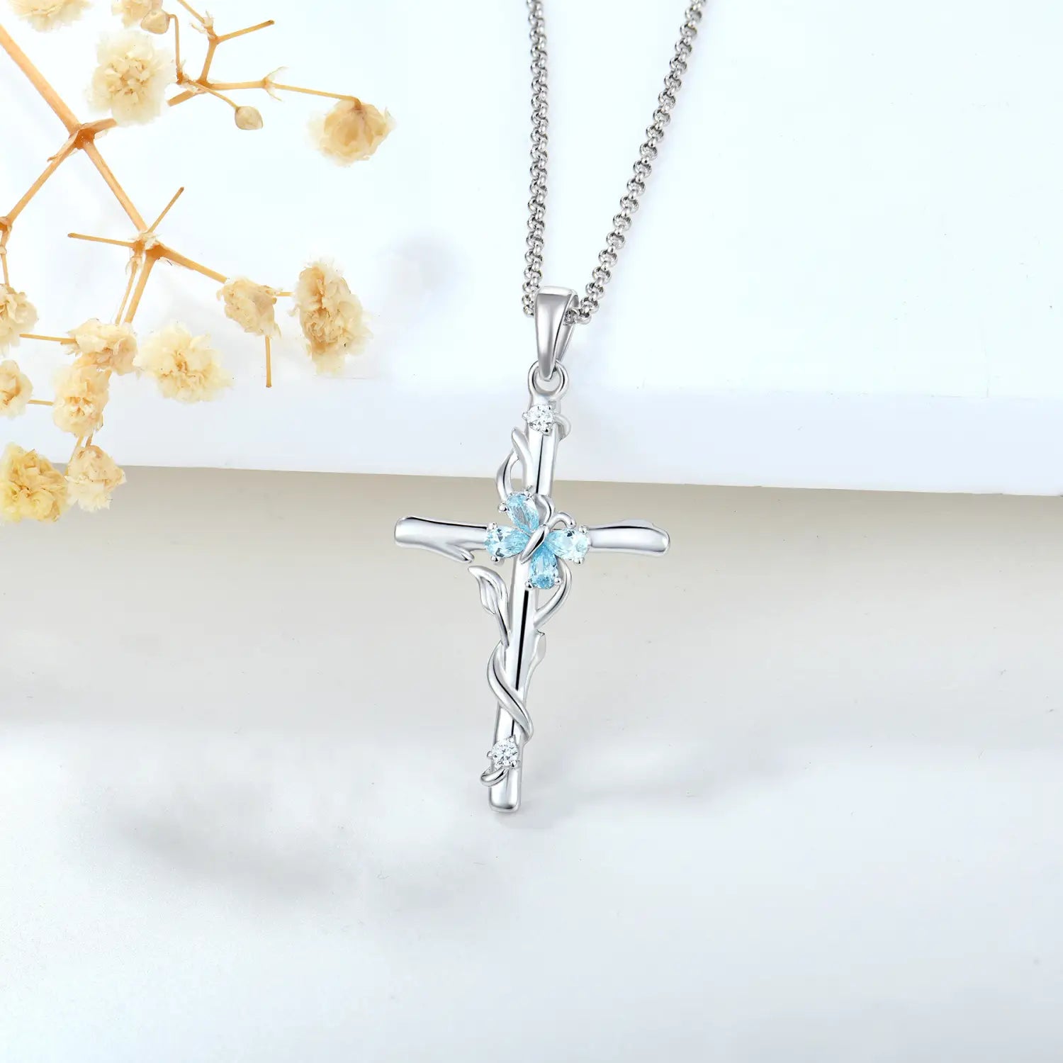 Silver cross necklace sterling featuring a delicate vine design with three light blue gemstones and small clear crystals in sterling silver for women.