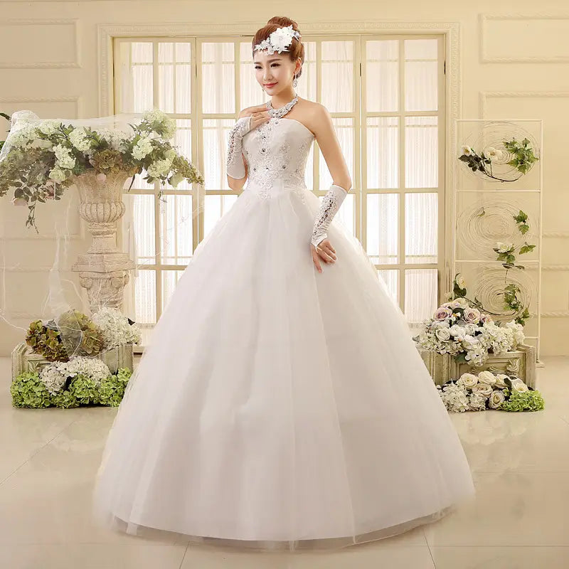 A white strapless korean style tube wedding dress with a fitted lace and beaded bodice flowing into a voluminous tulle skirt.