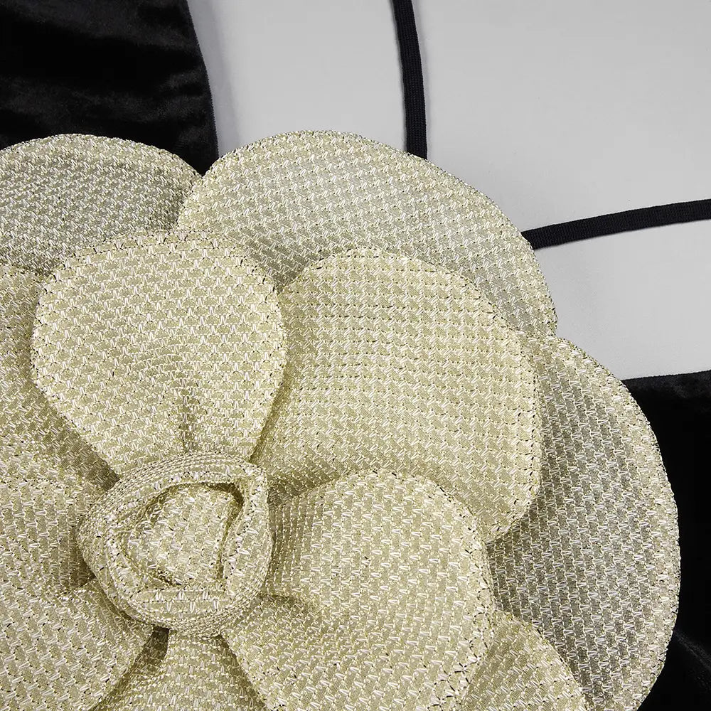 A shimmering gold woven flower embellishment with a textured interlaced pattern on the back of a black camisole backless slim fit velvet floral gown.