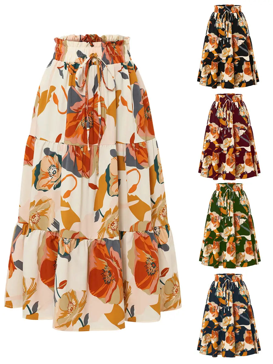A tiered floral maxi skirt in cream orange and muted green tones featuring a pleated floral print and a floral print elastic drawstring waistband.