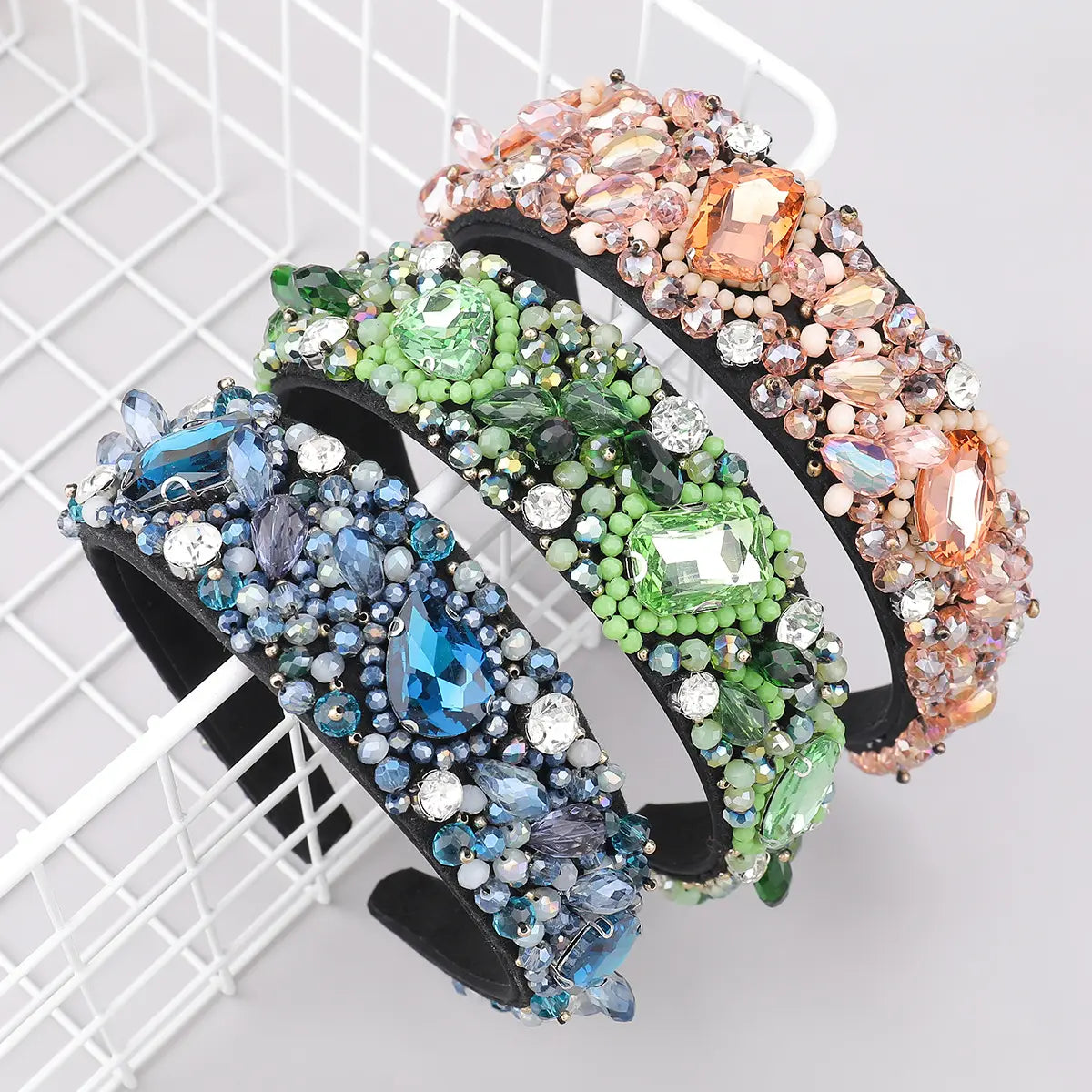 Three ornate black headbands adorned with sparkling crystal geometric glass rhinestones in vibrant blue green and peach hues.