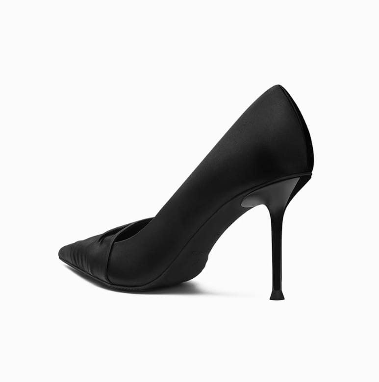 Black cloth satin high heels with ruched detailing, pointed toe, and slender stiletto heel shown from the side.