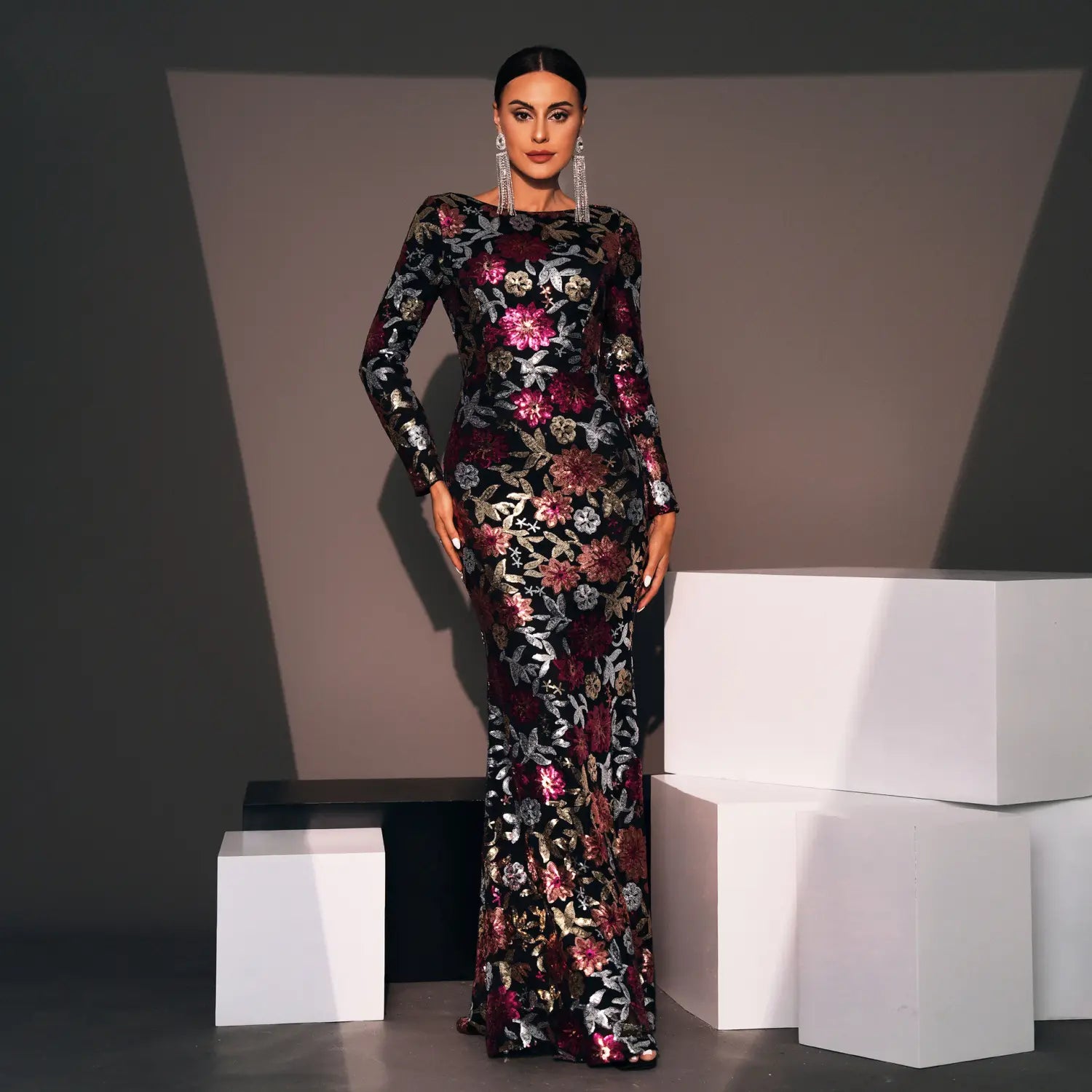 A long sleeve evening gown long made of black fabric with intricate floral embroidery featuring vibrant pink and metallic silver accents.