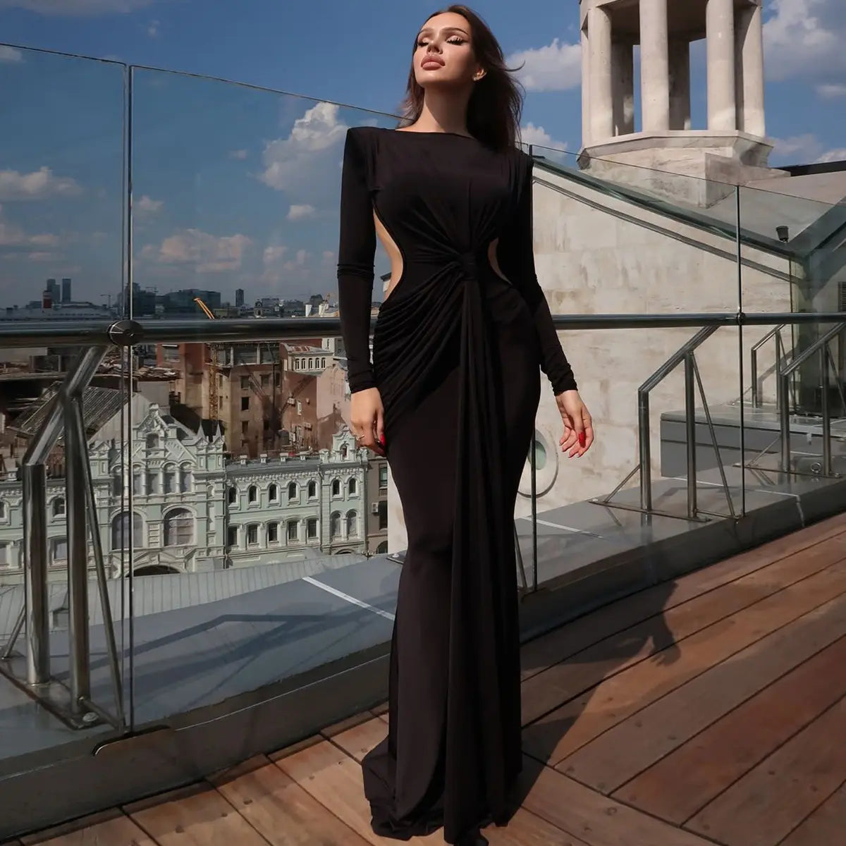 A sleek black long sleeve dress with a fitted silhouette and a sexy hot girl hollow out waist detail flowing elegantly to the floor.