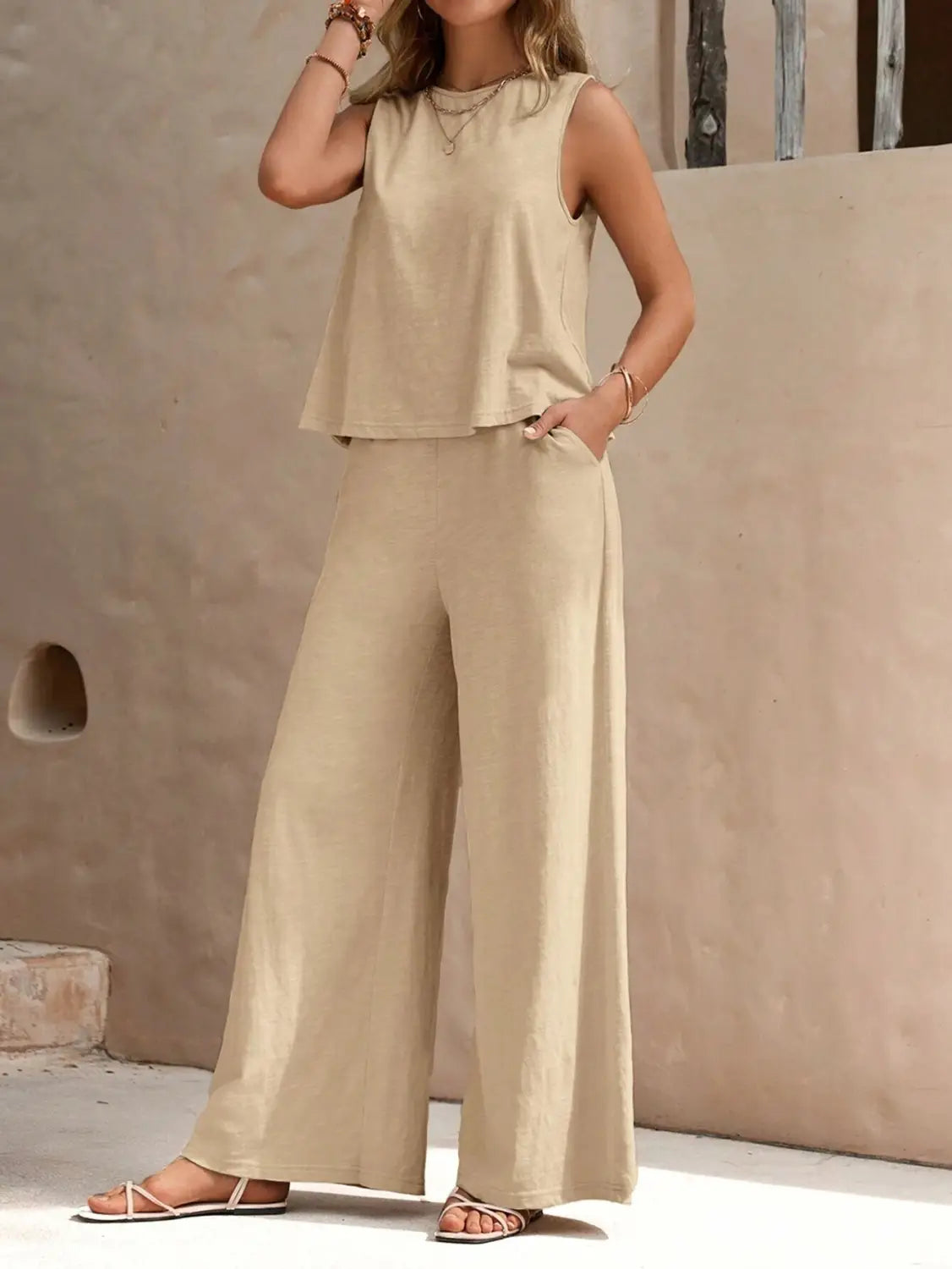 Beige sleeveless top with a relaxed flowing fit and subtle tiered hemline paired with black casual loose pants set designed for comfortable everyday wear.