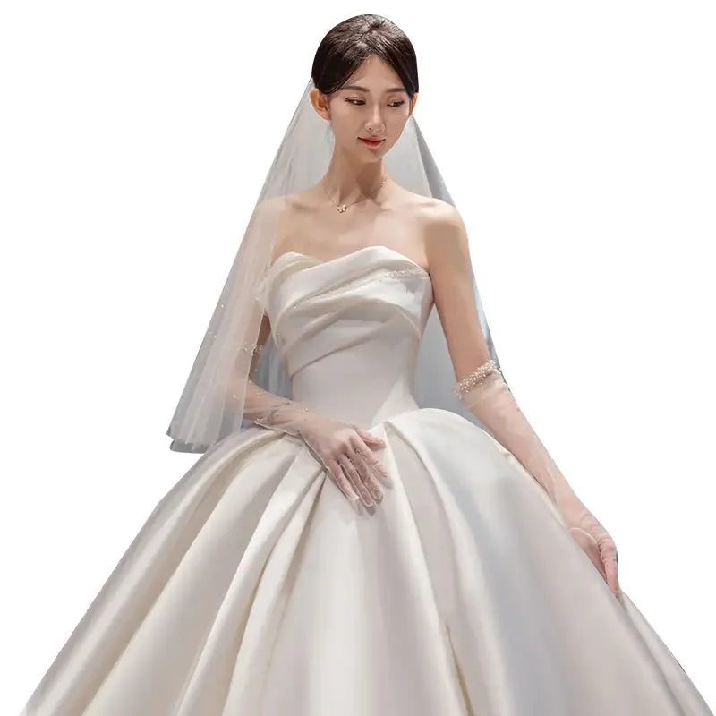 A strapless ivory satin wedding gown in temperament princess style featuring a full skirt and delicate lace veil showcasing classic style french satin elegance.