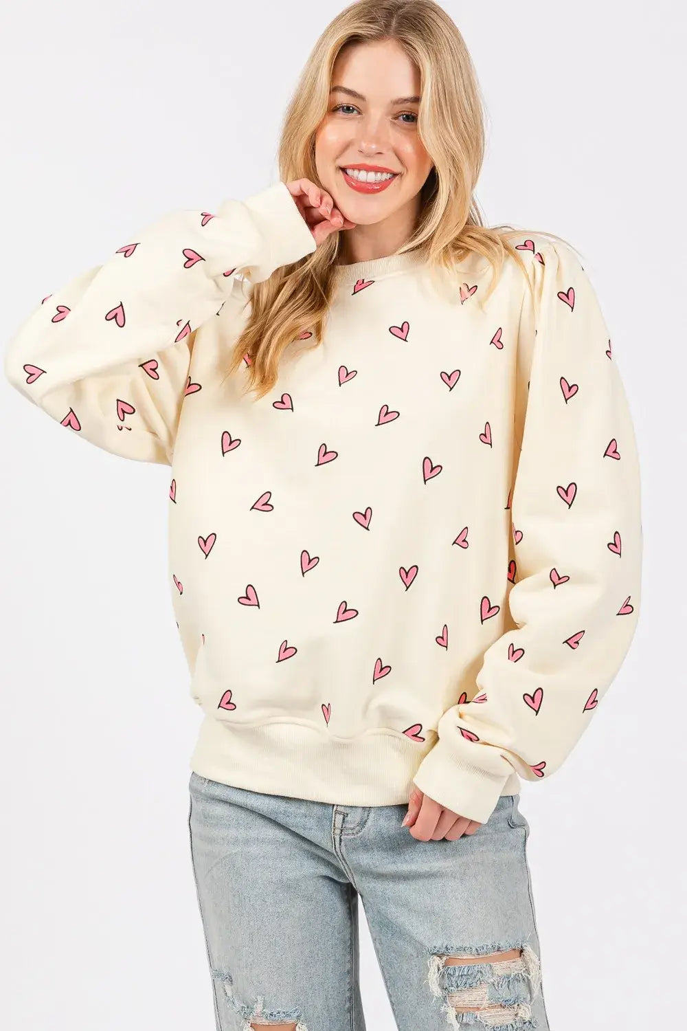 Cream-colored sage fig heart printed long sleeve sweatshirt featuring a playful pattern of small pink hearts across the fabric.