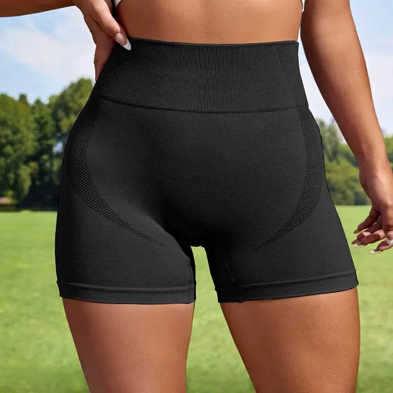 Black high-waisted women sport seamless shorts with a ribbed waistband and mesh panel detailing suitable as seamless short leggings.