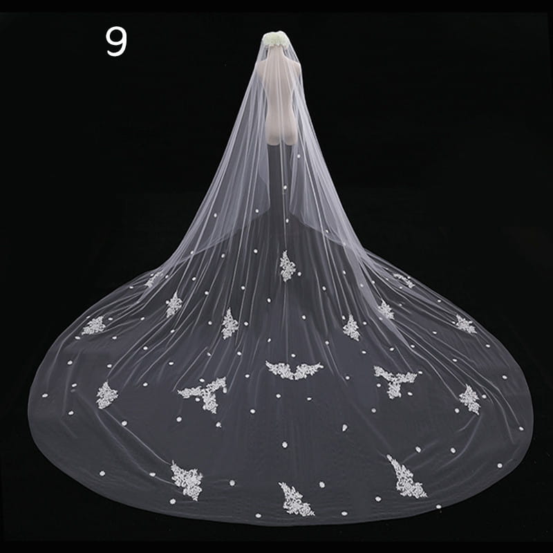 A delicate white lace wedding veil with intricate floral embroidery and pearl-like embellishments in a meters wide style.