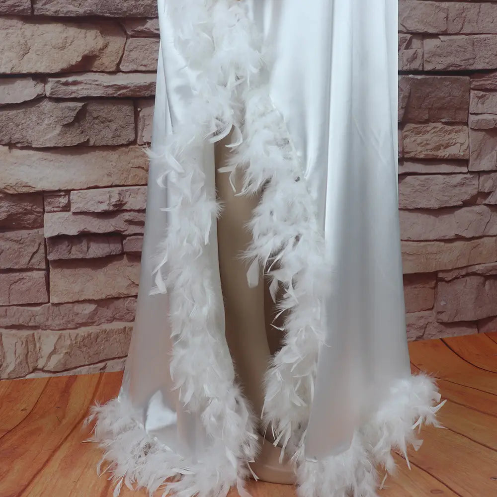 white satin robe with fluffy white feather trim along the edges in a loose dress luxury style fully surrounded by feather details