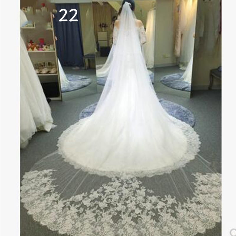 a long white bridal veil with intricate lace detailing along the hemline in a meters wide style designed for weddings