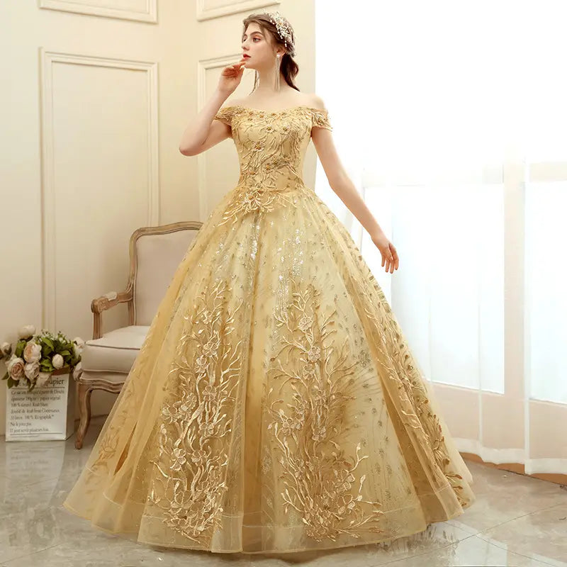 A shimmering gold off-the-shoulder solo performance costume featuring intricate floral embroidery and a voluminous tulle performance costume tutu skirt.