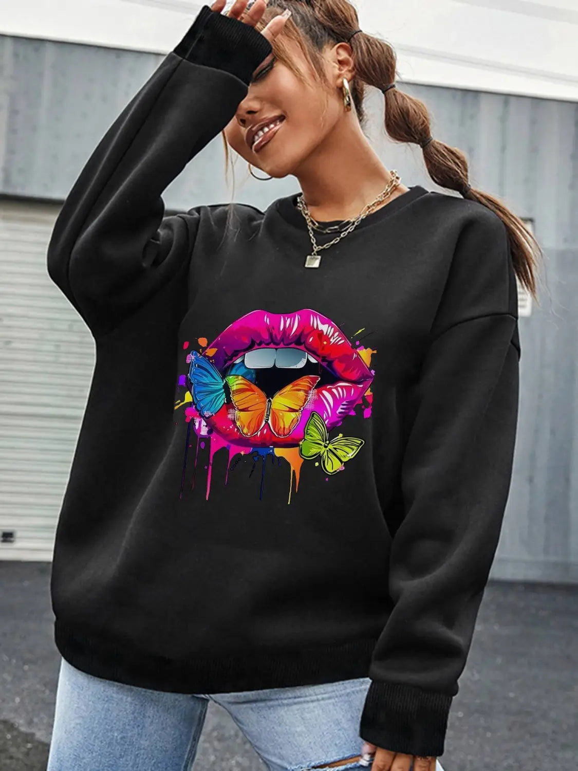 black crew neck sweatshirt featuring a vibrant colorful graphic of lips with butterflies and paint drips showcasing a unique design on a neck sweatshirt.