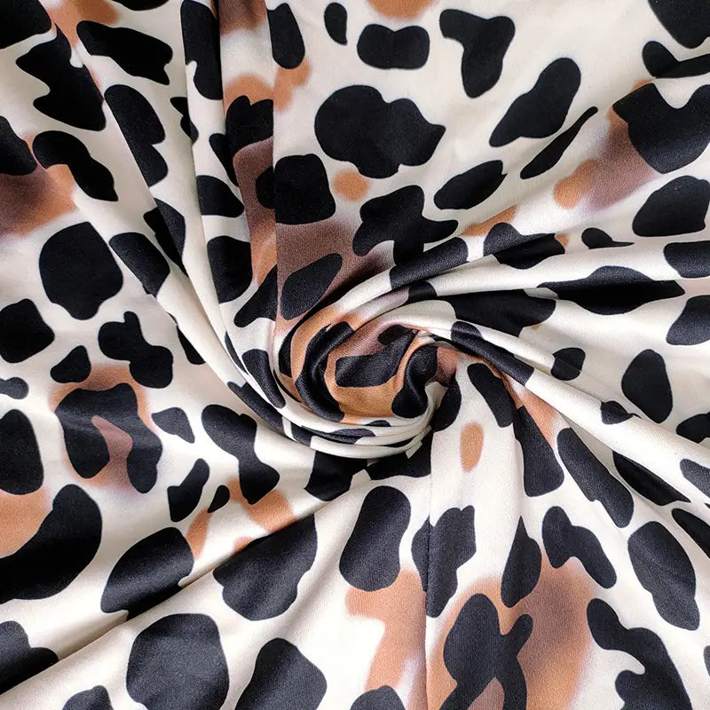 A soft flowing fabric featuring a bold black and tan leopard print on an off white base for a leopard print jumpsuit plus size women’s.