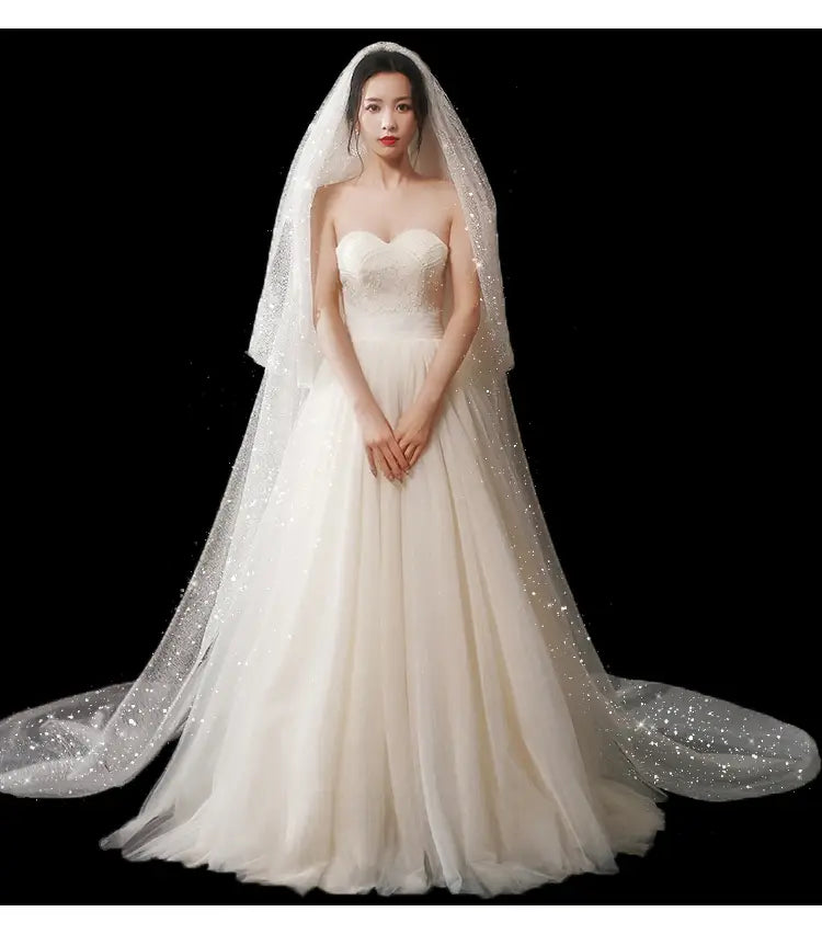 a flowing ivory bridal wedding dress with a strapless sweetheart neckline and a sparkling wide style tulle veil secured by a hair comb
