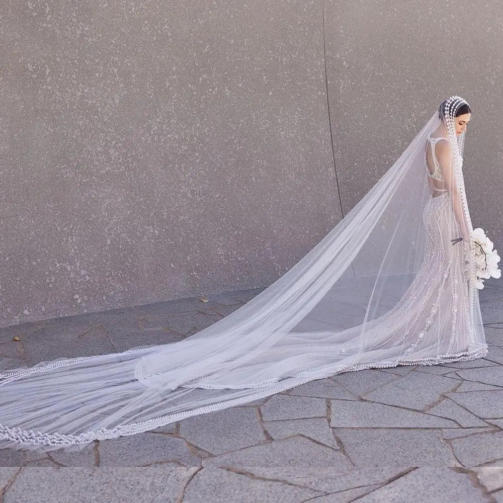 a long flowing white yarn wedding bridal veil with delicate beading along the edge and a broadband hair comb matching headpiece