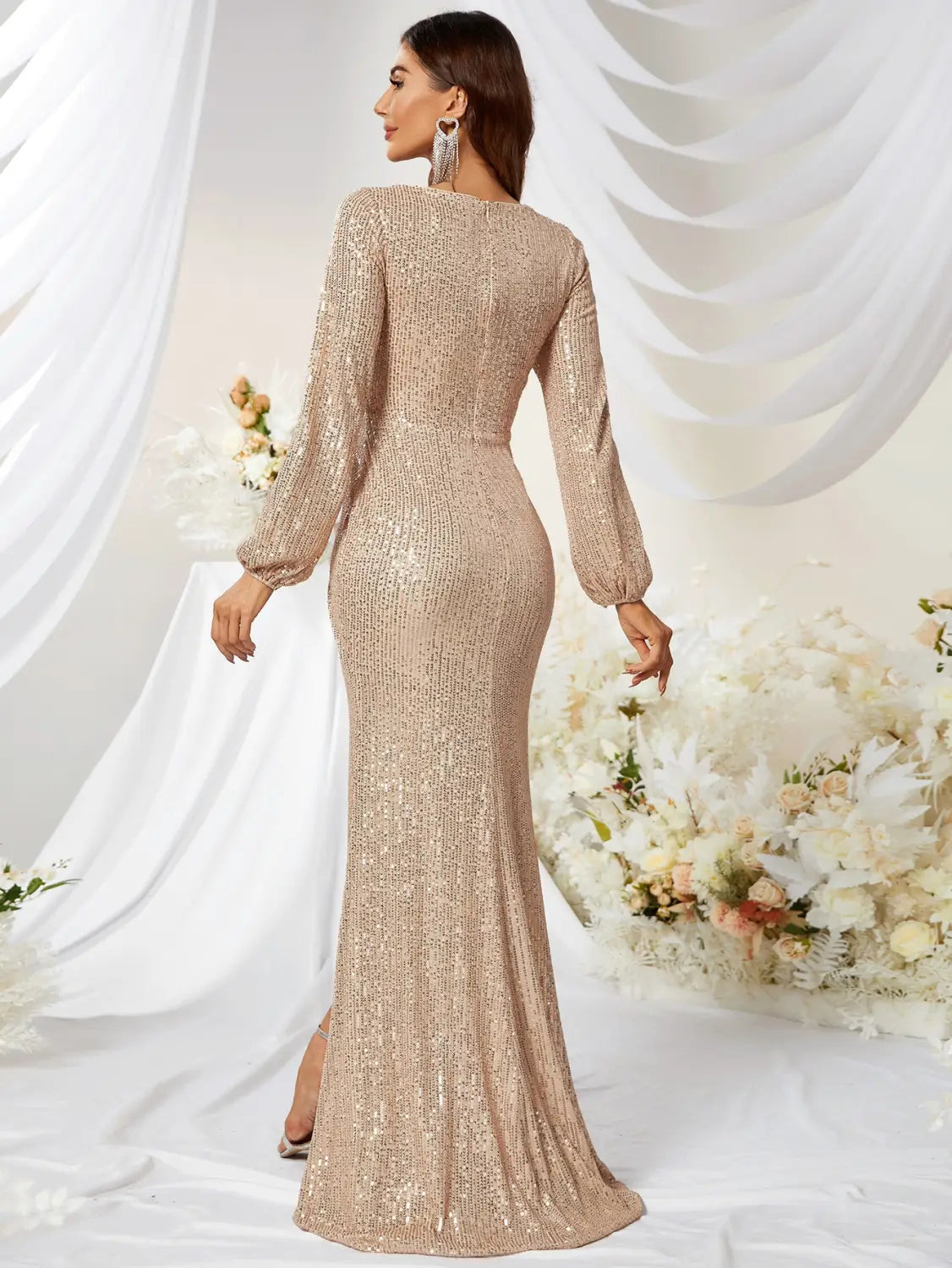 A shimmering champagne-colored sequined long sleeve high slit fishtail dress with a fitted silhouette.