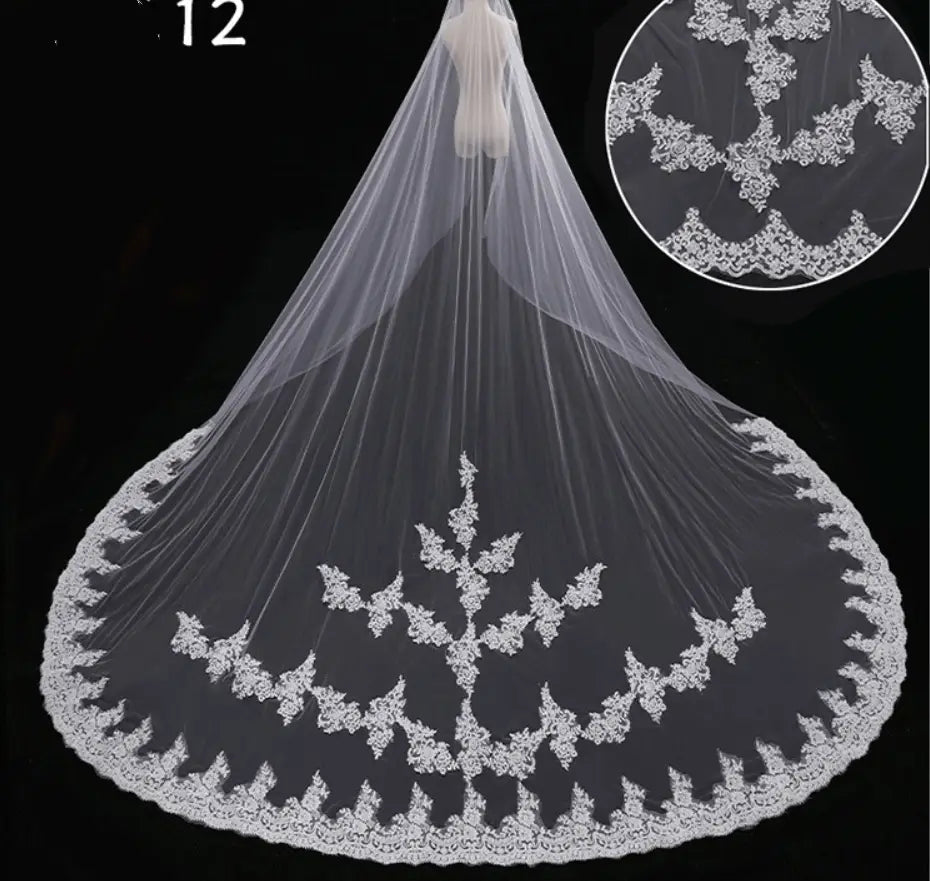 a delicate white lace wide style bridal wedding dress veil with intricate floral embroidery along the edge and a flowing sheer fabric attached to a hair comb