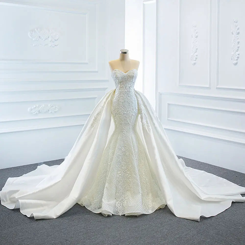 A white lace mermaid wedding dress wears two fishtail train with intricate detailing and a flowing train.