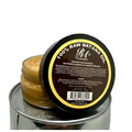 A round dark brown jar with black lid and yellow border contains 100 percent raw natural batana hair oil from r&g cosmetics