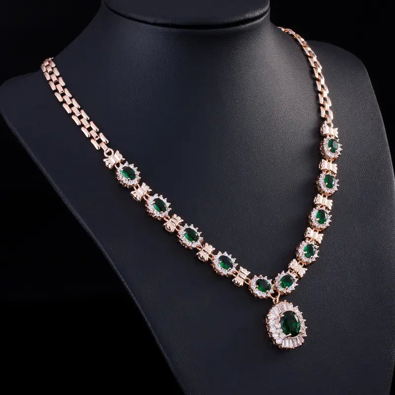 A rose gold necklace from the big brand retro zircon four-piece suit featuring oval emerald stones surrounded by clear crystals and a larger central pendant hanging elegantly from the chain.