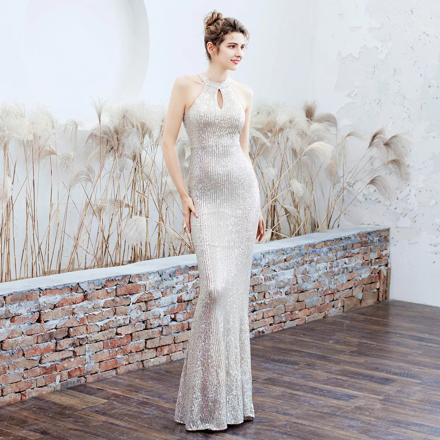 A shimmering silver sequined white sequin polyester fiber mermaid evening dress with a halter neckline and keyhole detail.