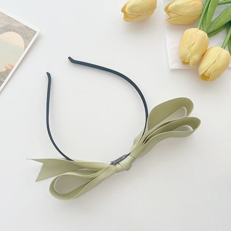 A delicate sage green french satin bow headband with a sleek black elastic band for women.