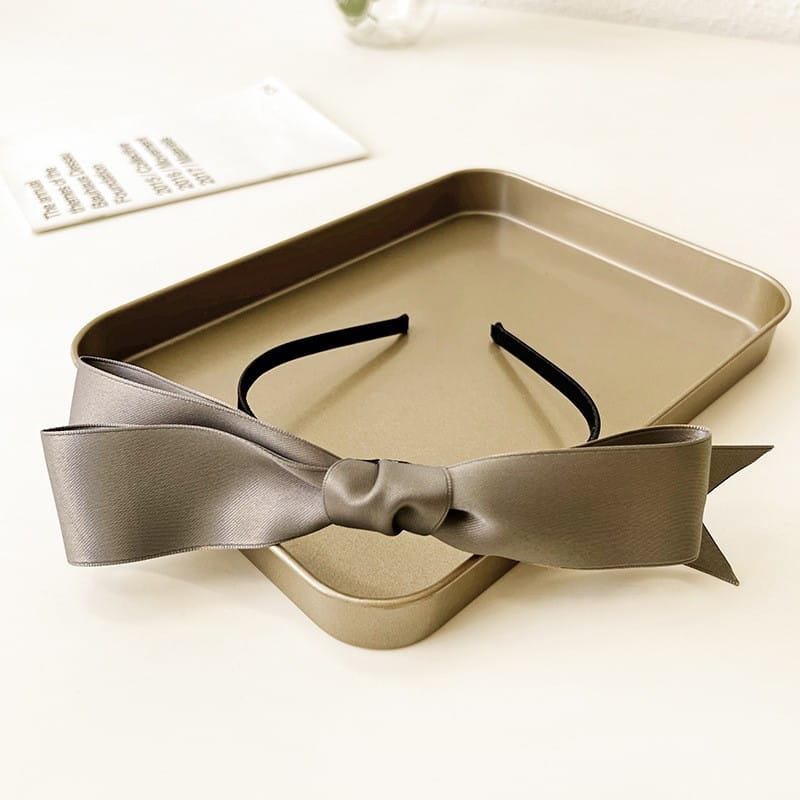 A sleek matte black bow headband for women featuring a large gray french satin bow with a satin finish.