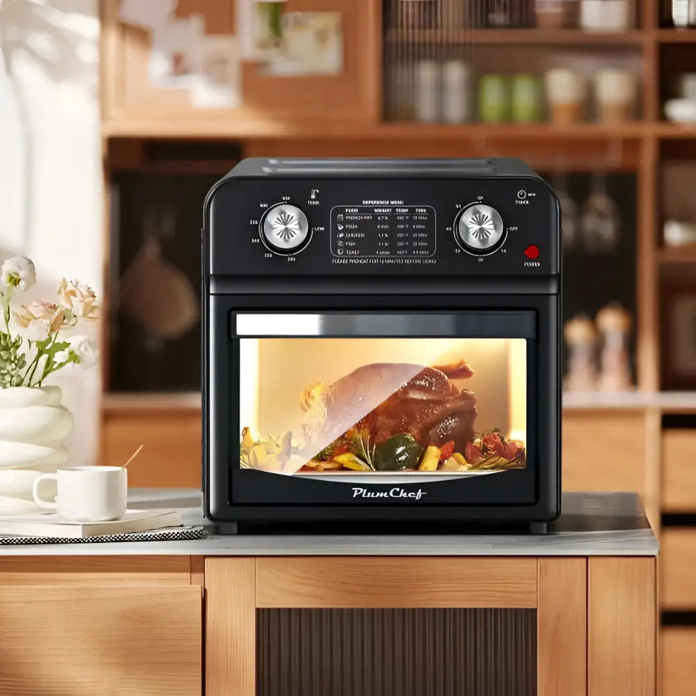 Black plumchef 12 liter air fryer oven with dual knob control and glass door roasting turkey and vegetables inside