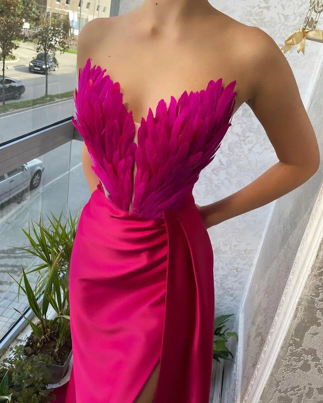 A vibrant fuchsia strapless gown with a feathered bodice and satin skirt featuring feathers sweeping the floor in luxury women’s fashion.