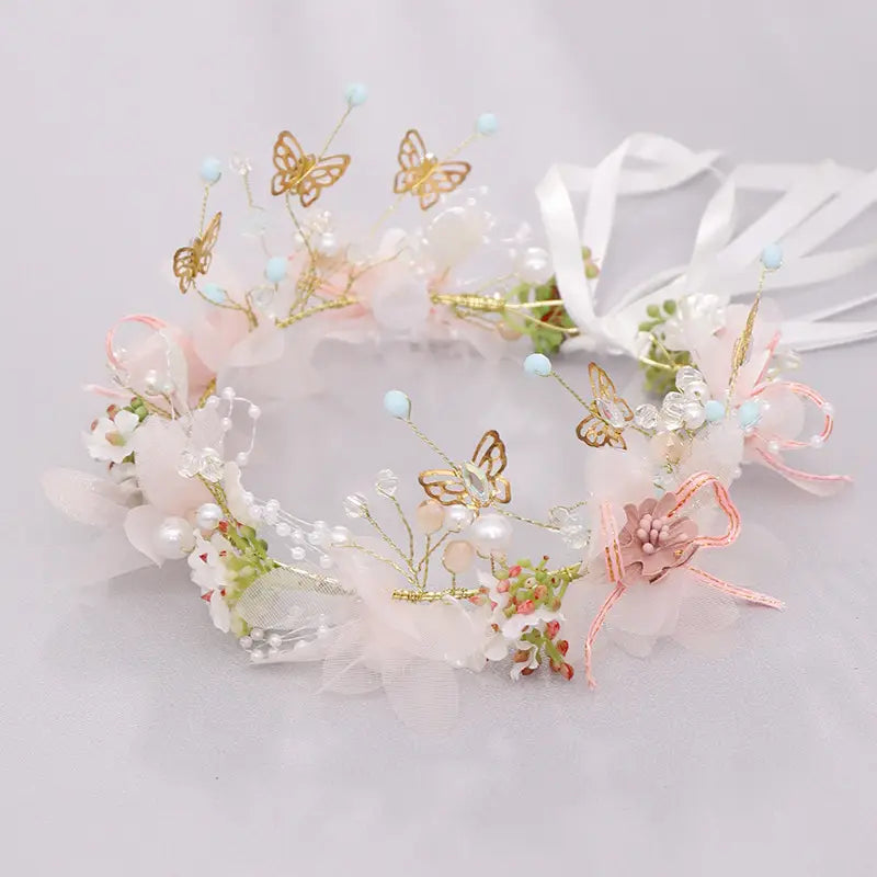a luxury floral bridal wreath featuring delicate pink and white flowers adorned with gold butterfly charms, pearls, and sheer fabric accents, perfect for luxury women’s fashion.