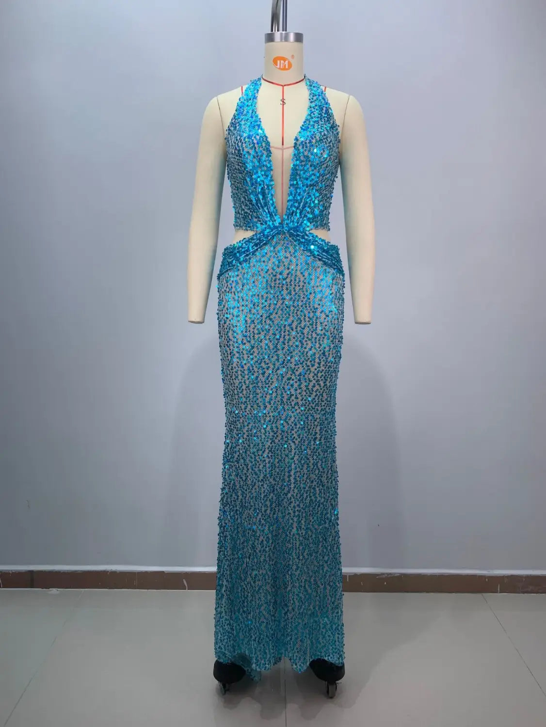 A shimmering turquoise sequined evening gown with a deep plunging neckline and cut-out waist detail designed for a slimming party stage host in a slim slimming party mermaid style.