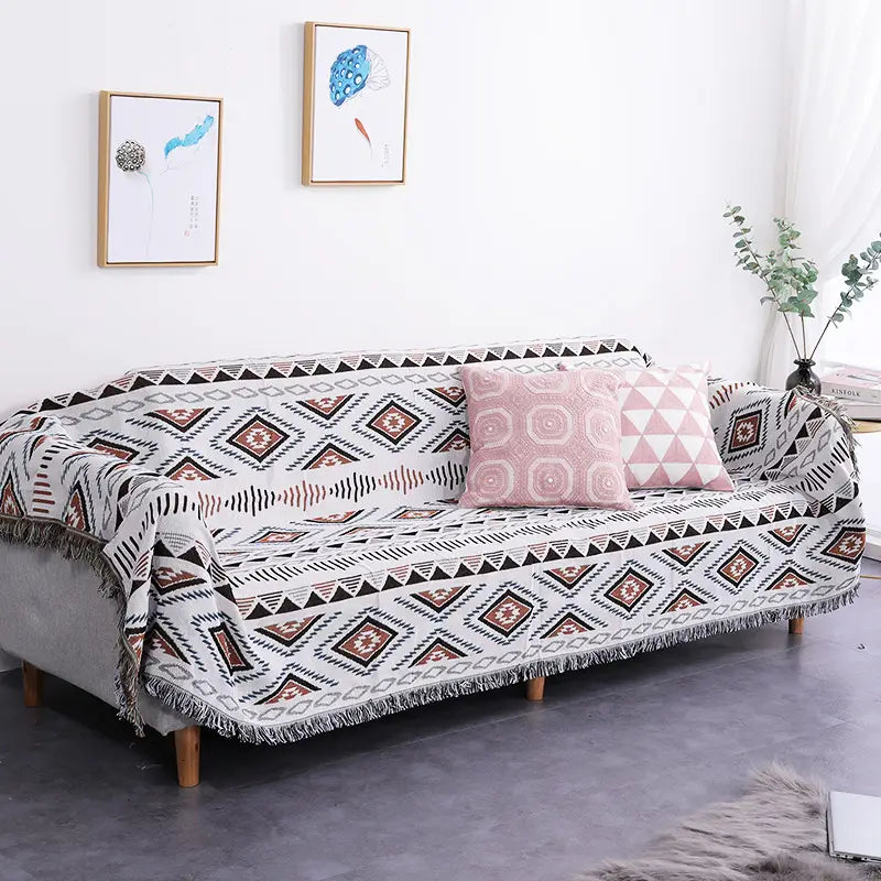 a cozy geometric woven fringed sofa blanket in white black and terracotta tones serving as a blanket sofa towel on a sofa