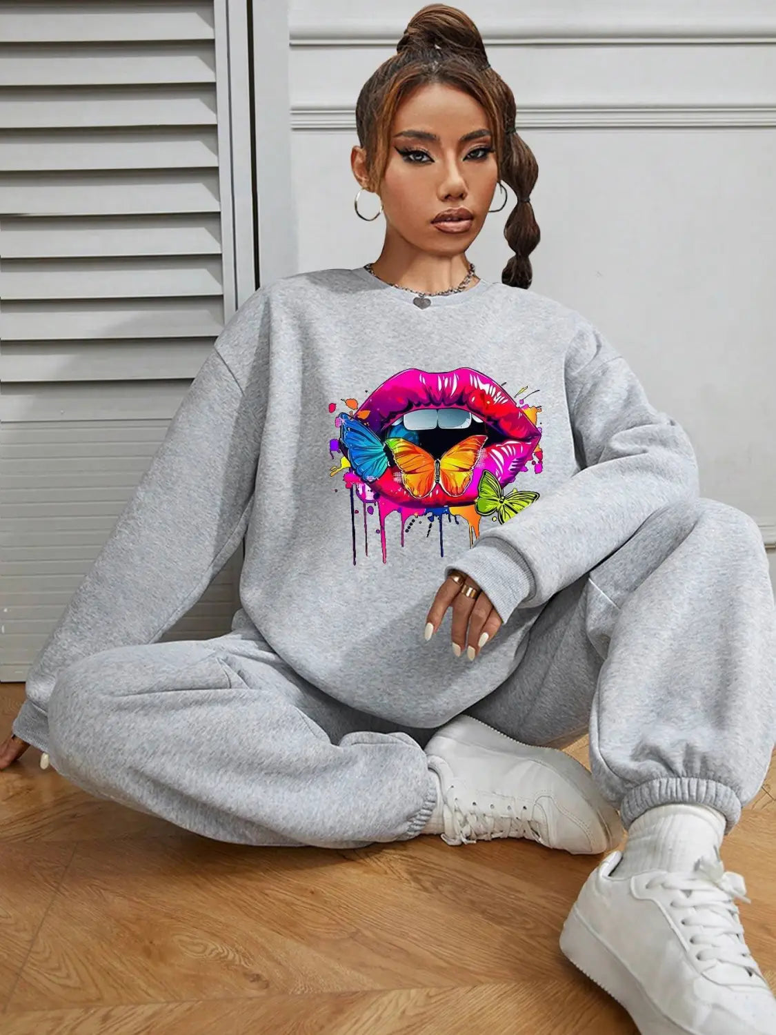 gray oversized crew neck sweatshirt featuring a vibrant dripping paint-style graphic of pink and purple lips with colorful butterflies on the front