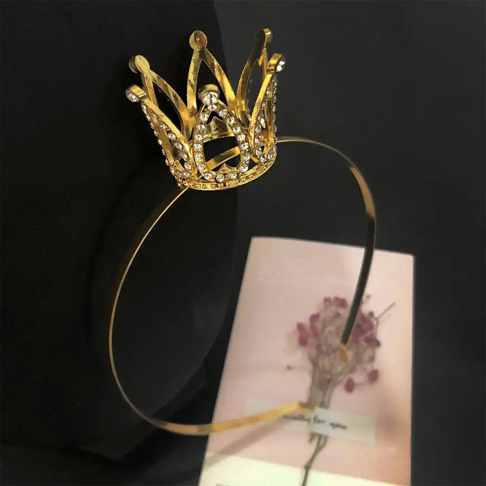 A delicate gold hair comb crown adorned with sparkling rhinestones featuring an intricate pointed design as crown rhinestone accessories for children.