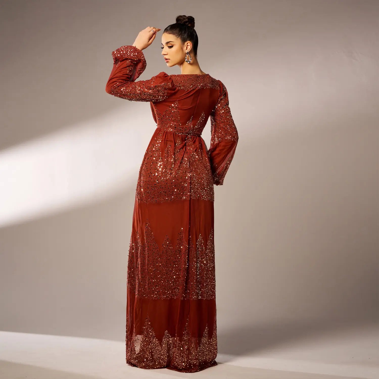 a rust-red shiny sequined evening dress with long puffed bell sleeves, a fitted waist, and intricate glittery embellishments along the bodice, skirt hem, and sleeve cuffs, perfect as a sexy long sequined gown.