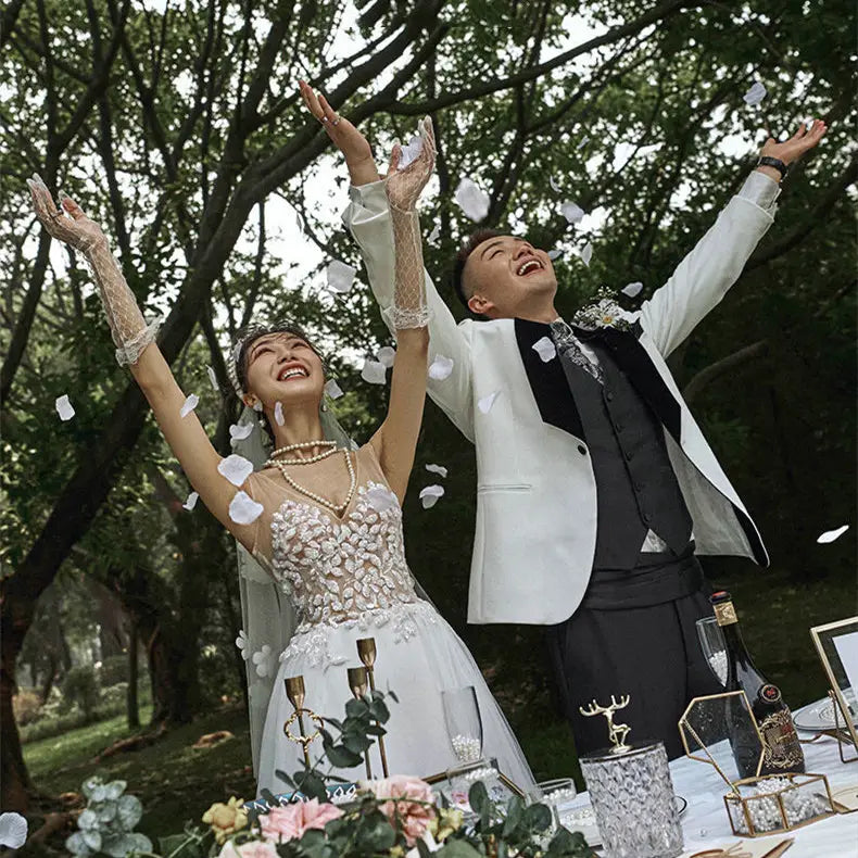 White lace wedding dress with floral embellishments and sheer veil designed for summer couple photo and couple photo shoot.