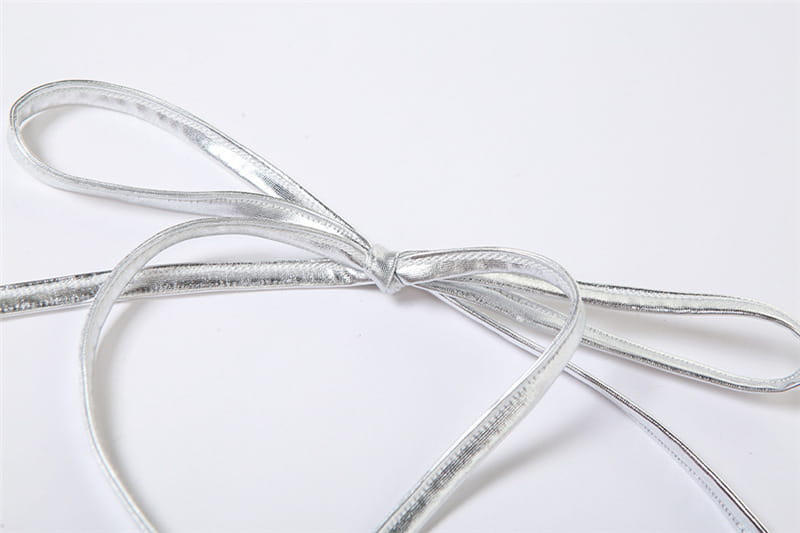 silver metallic ribbon tied into a bow on the back side of a halter backless sequined vest showcasing the backless sequined design.