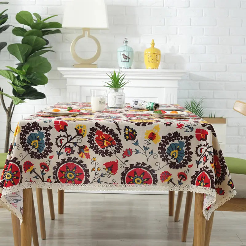 A vibrant cream-colored linen table cloth featuring bold red blue and yellow floral embroidery in a sunflower cotton and linen table design.