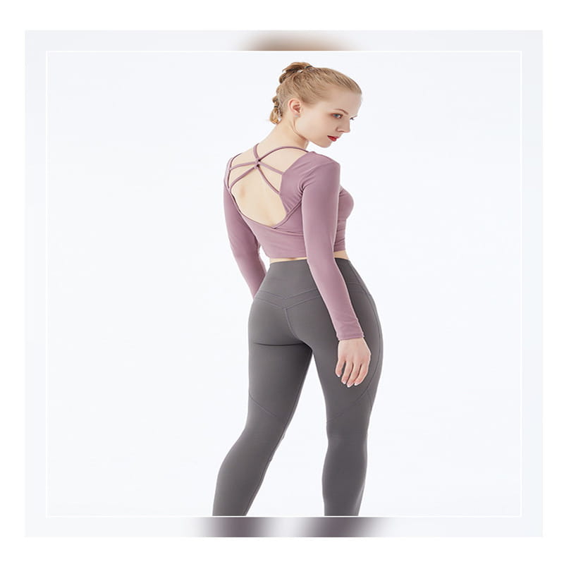 a mauve long sleeve yoga crop top with a crisscross strap back design paired with high-waisted gray leggings