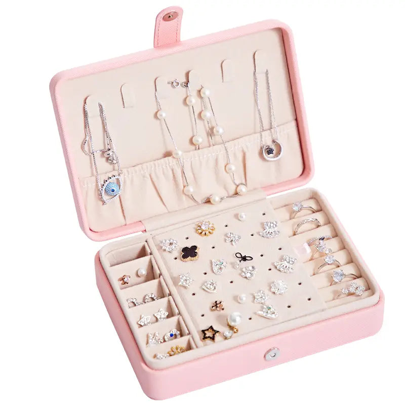 Pink faux leather multifunctional jewelry storage box with soft beige interior compartments and slots for necklaces earrings and rings featuring an integrated mirror for organized jewelry storage.