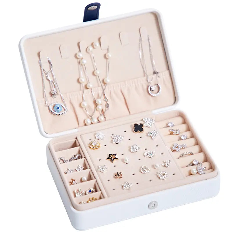 white rectangular multifunctional jewelry storage box with mirror features navy blue clasp and beige interior compartments holding various necklaces earrings and rings as a jewelry storage box
