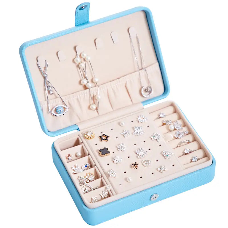 Light blue faux leather multifunctional jewelry storage box with beige velvet interior compartments and slots for necklaces earrings and rings featuring a built-in mirror.
