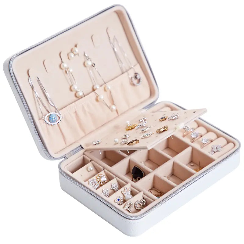 White leather multifunctional jewelry storage box with beige interior compartments, a flip-out tray for earrings, and a built-in mirror.